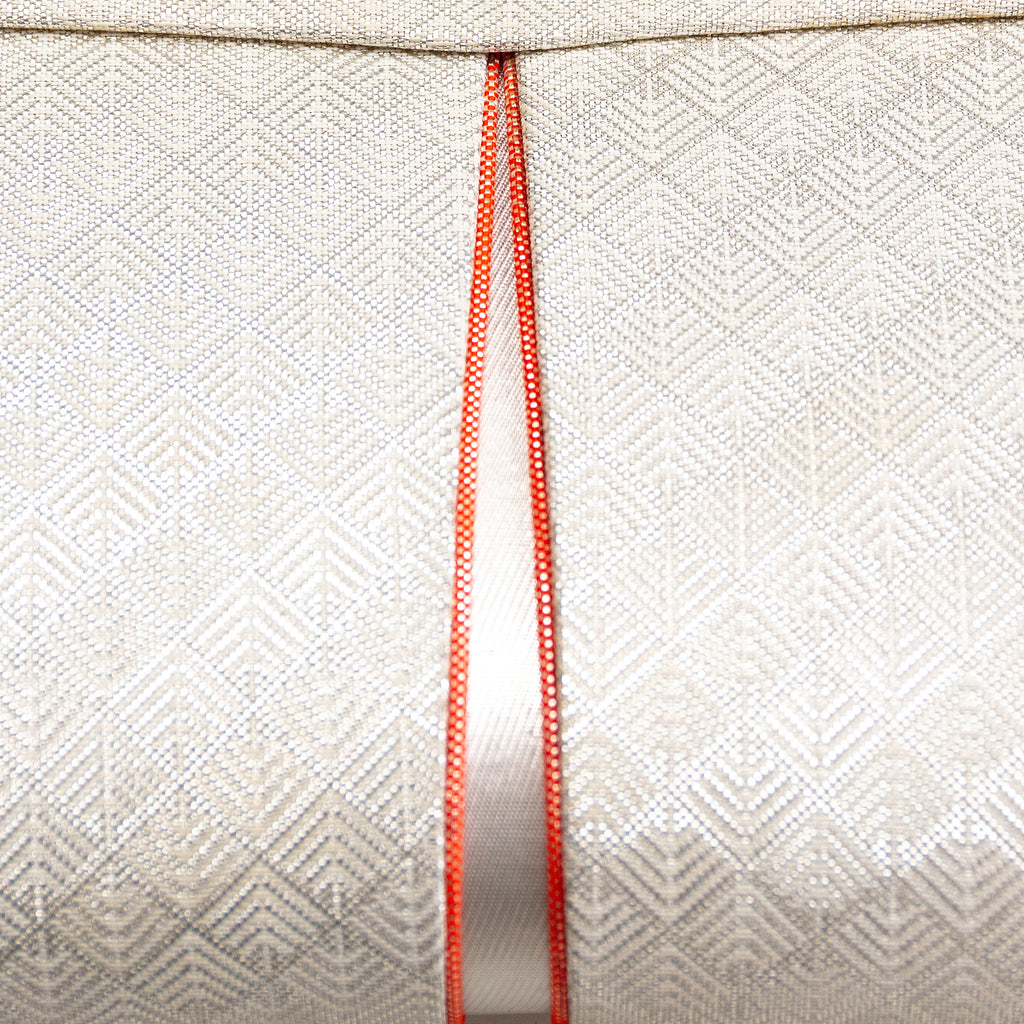 Close up of vintage Japanese silk clutch bag front with silver patterned weave and orange trim accent panel.