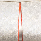 Close up of vintage Japanese silk clutch bag front with silver patterned weave and orange trim accent panel.