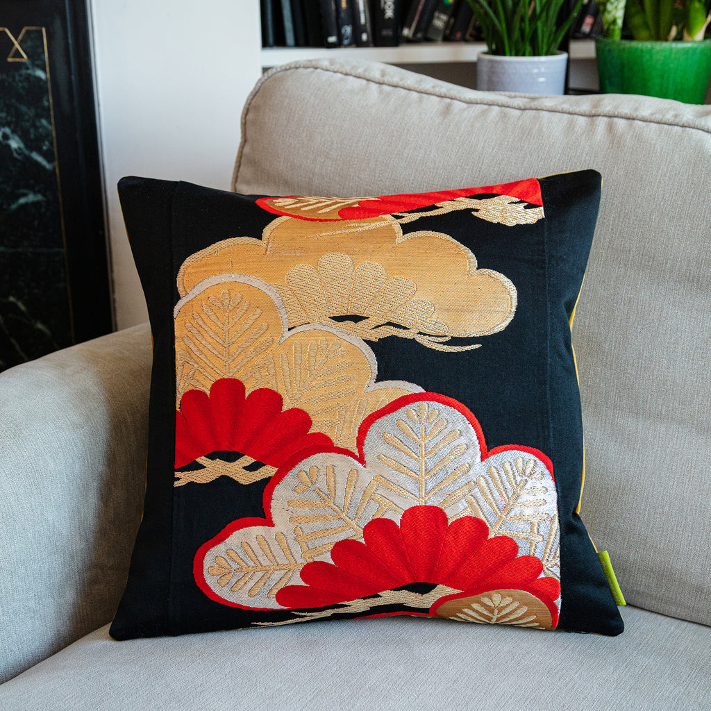 Close-up of the black silk fabric, highlighting the smooth texture and subtle sheen of the Obi pillow's gold velvet and