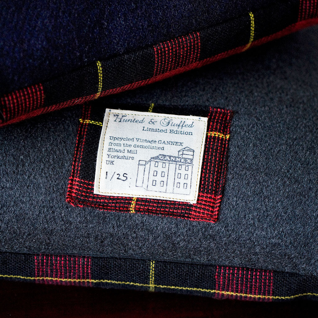 Close-up of textured grey wool tartan fabric highlighting the vintage 1960s Gannex pattern and subtle color variations.