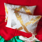 Two cream, gold and silver vintage obi pillows on a bright red silk throw on a sofa.