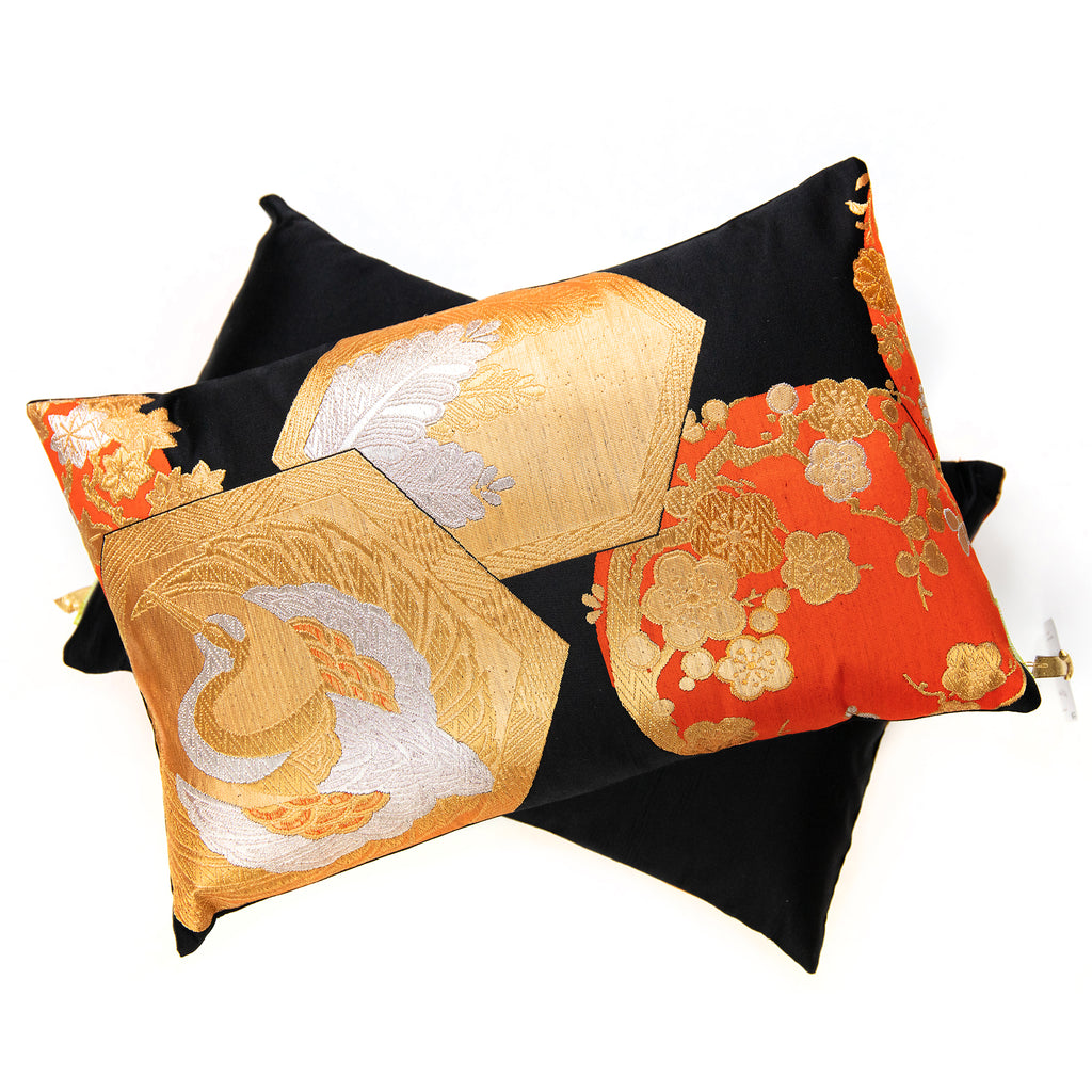 Black and gold Japanese obi pillow on top of a plain black rectangular pillow on a white background.