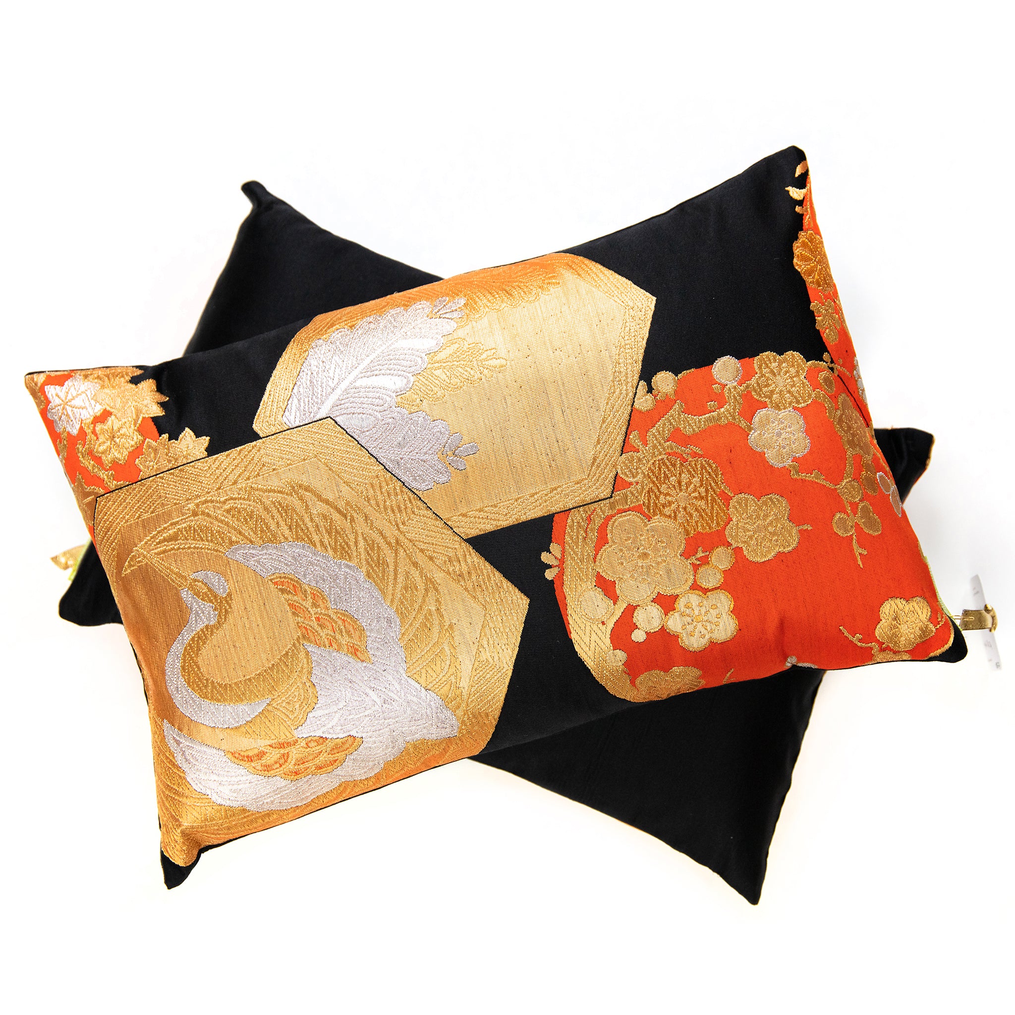 Black and gold Japanese obi pillow on top of a plain black rectangular pillow on a white background.