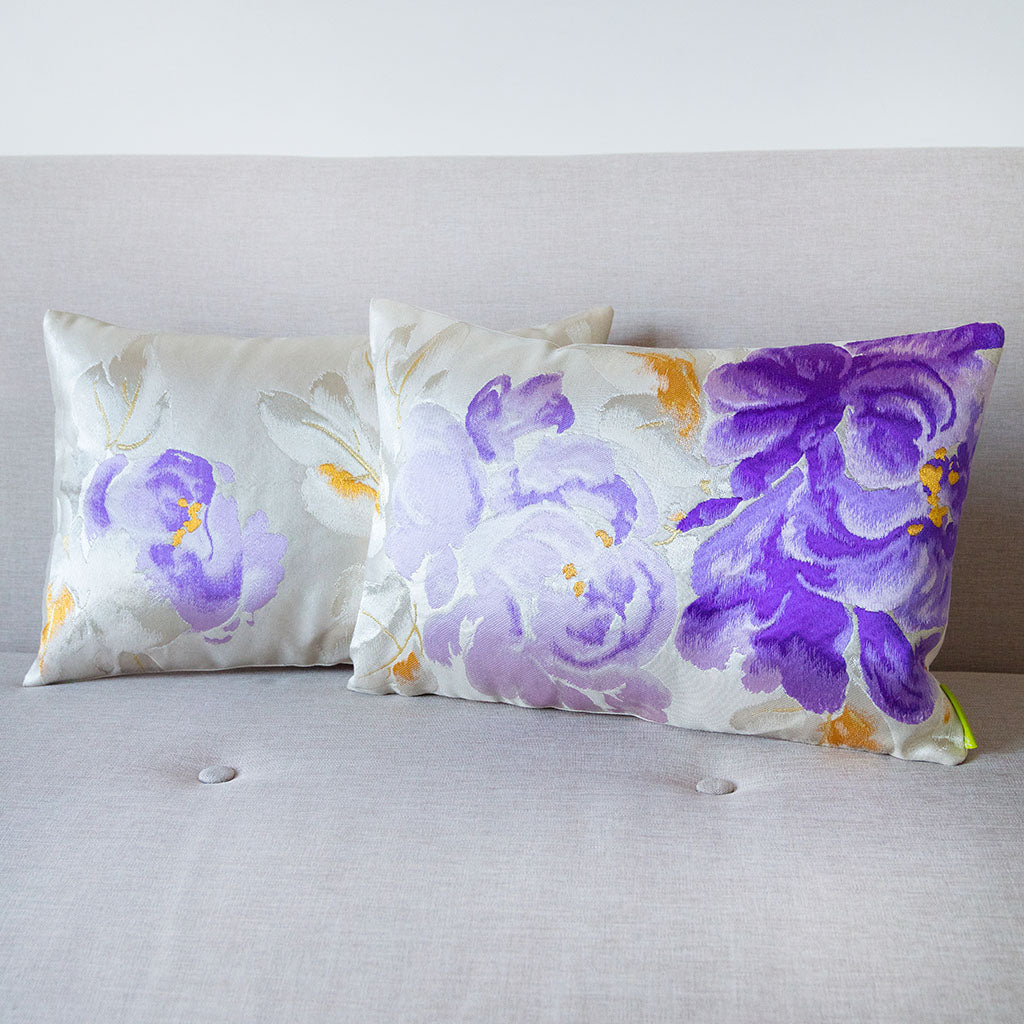 Pair of pale silver and lilac floral cushions made from vintage Japanese obi silk on a neutral sofa.