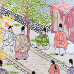 Close-up of embroidered obi silk depicting intricate street scene details with vibrant Nishijin craftsmanship.