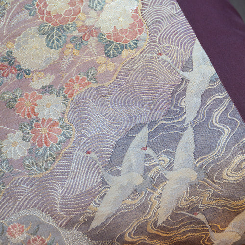 Close-up of vintage silk obi cushion in mauve and gold, flying cranes, mountains, swirling stream. Made from vintage Japanese obi silk and neutral velvet.