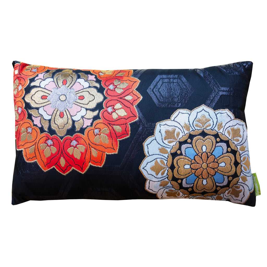 A black silk vintage Japanese obi cushion with stylised red and blue embroidered flowers on a dark background, with a geometric pattern.