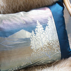 Close up of the blue silk  obi cushions front showing mountain and silver trees scene catching the light.