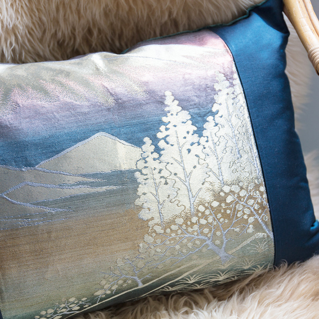 Close up of the blue silk  obi cushions front showing mountain and silver trees scene catching the light.