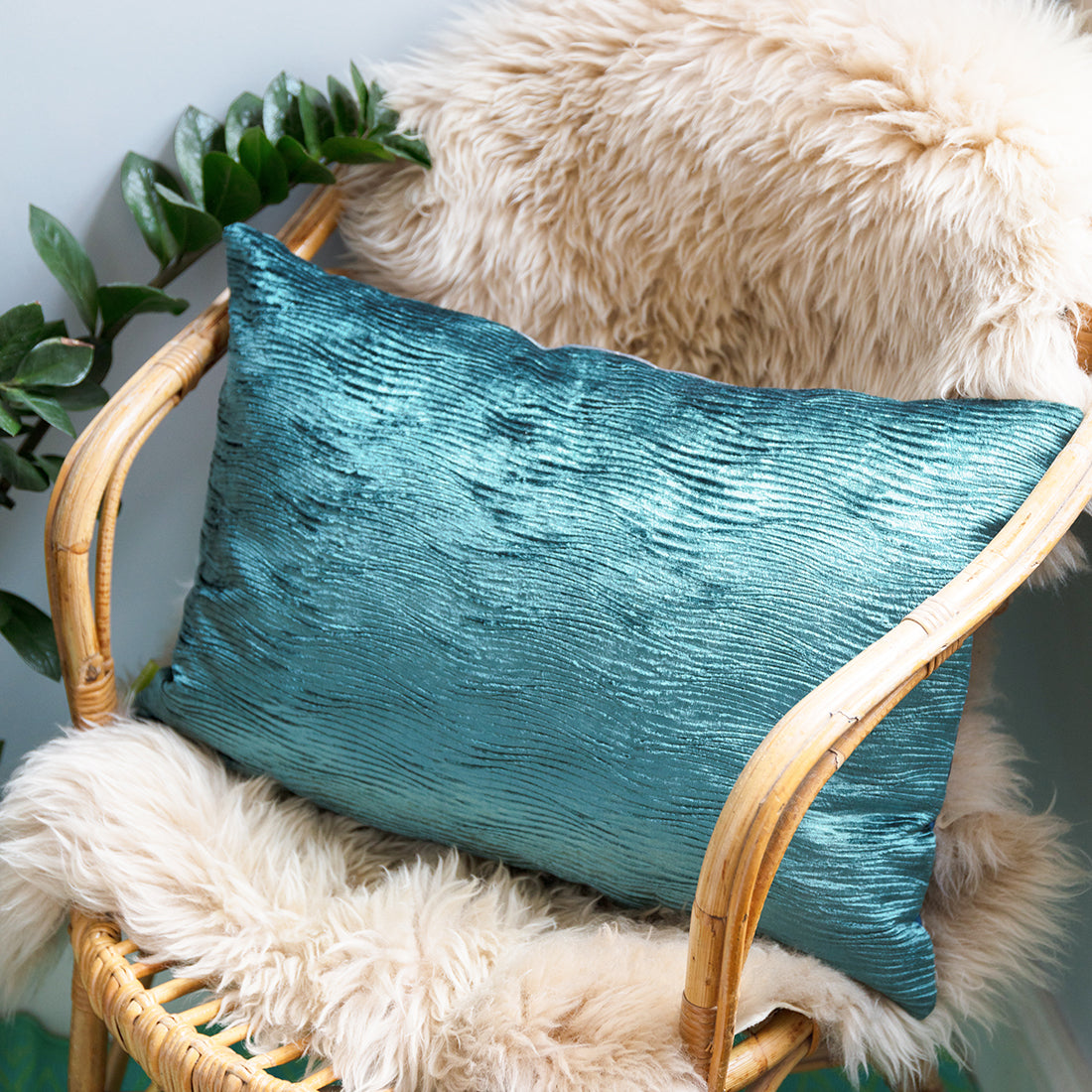 Reverse of the rectangular obi cushion is a textured blue designer velvet, displayed on a cane chair.