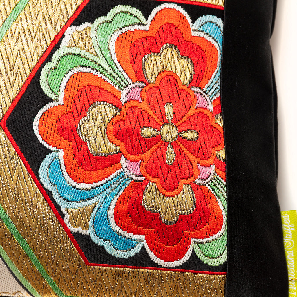 Red and gold floral pattern detail on a black silk vintage obi pillow.