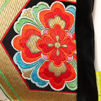 Red and gold floral pattern detail on a black silk vintage obi pillow.