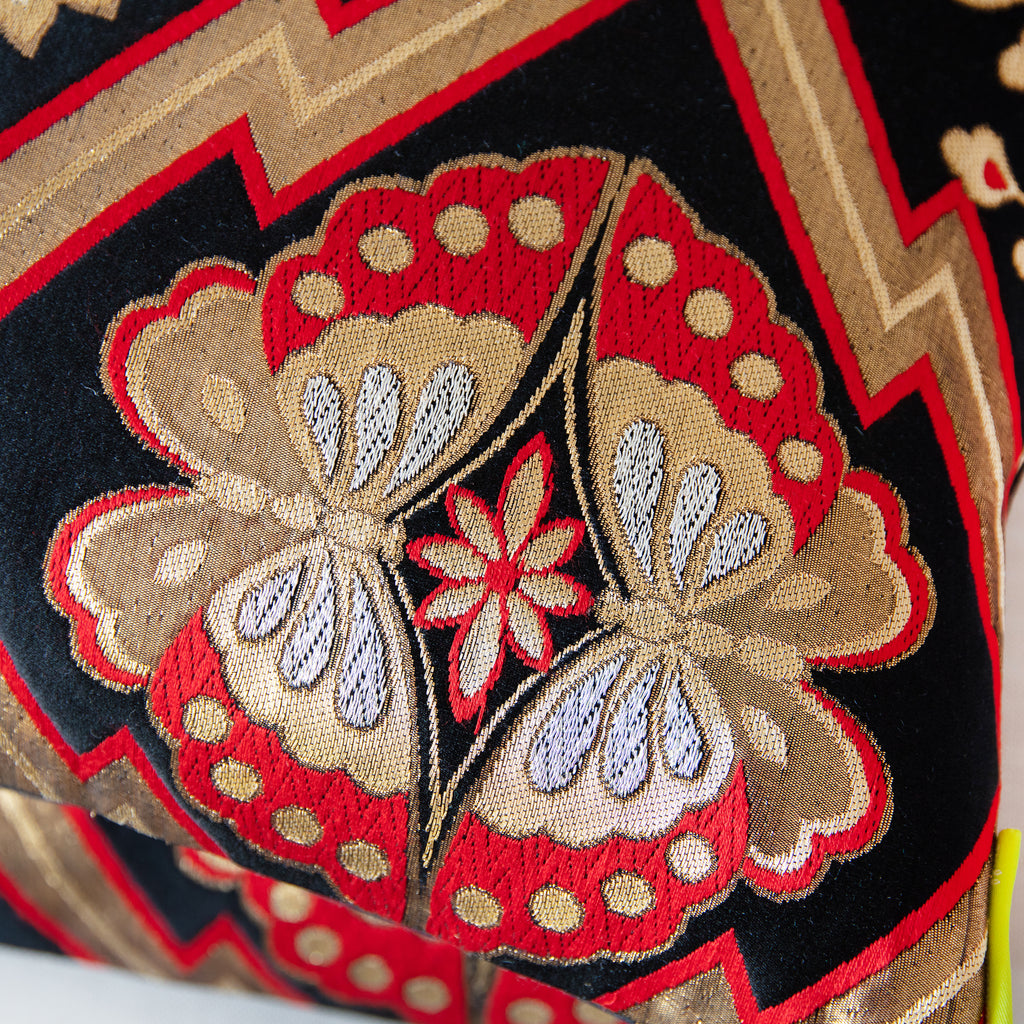 Detail of two butterfly symbols on a vintage black silk Japanese cushion.
