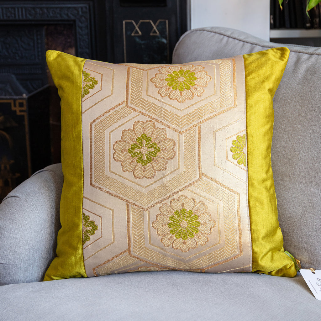 Close-up of gold embroidery and subtle pinstripes on the Obi cushion’s vivid chartreuse velvet fabric from a top-down angle.