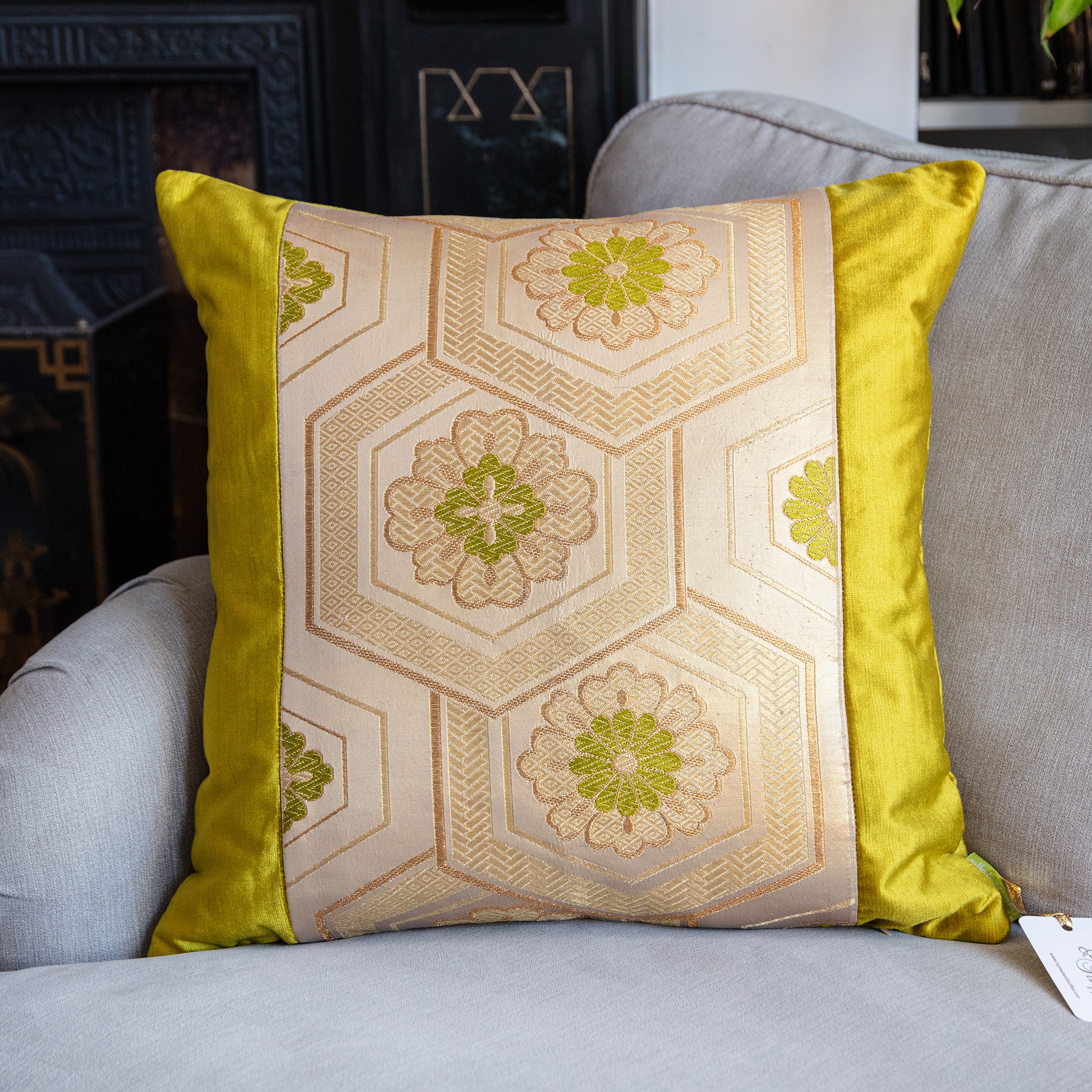 Close-up of gold embroidery and subtle pinstripes on the Obi cushion’s vivid chartreuse velvet fabric from a top-down angle.