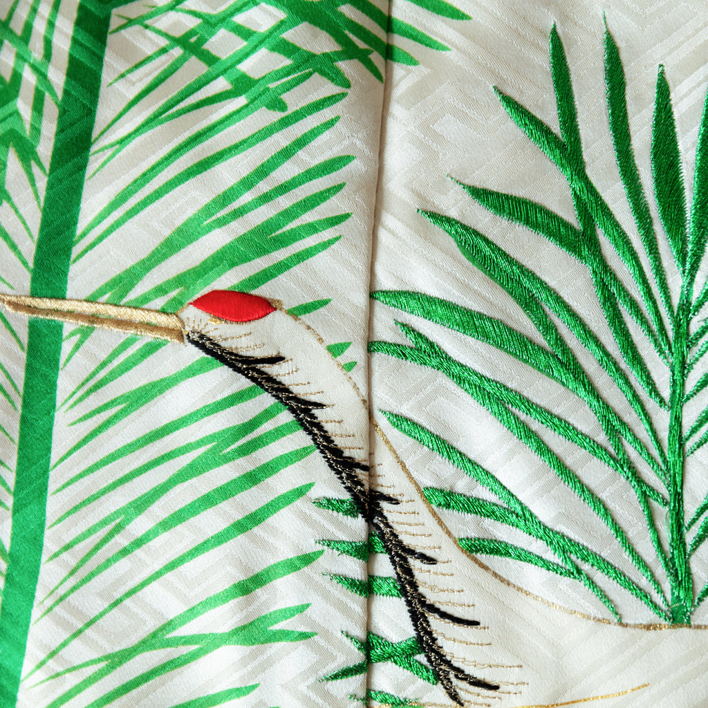 close up of silk throw made from vintage kimono silk, crane head over green embroidered pine needles, on woven white silk base.