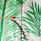 close up of silk throw made from vintage kimono silk, crane head over green embroidered pine needles, on woven white silk base.