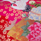 Close-up of pink silk and velvet textures highlighting intricate crane embroidery and vintage Uchikake style on the pillow