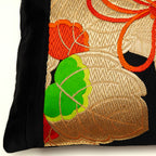 View of a corner of a vintage Japanes eobi pillow with black silk border and golden kiri leaf pattern.