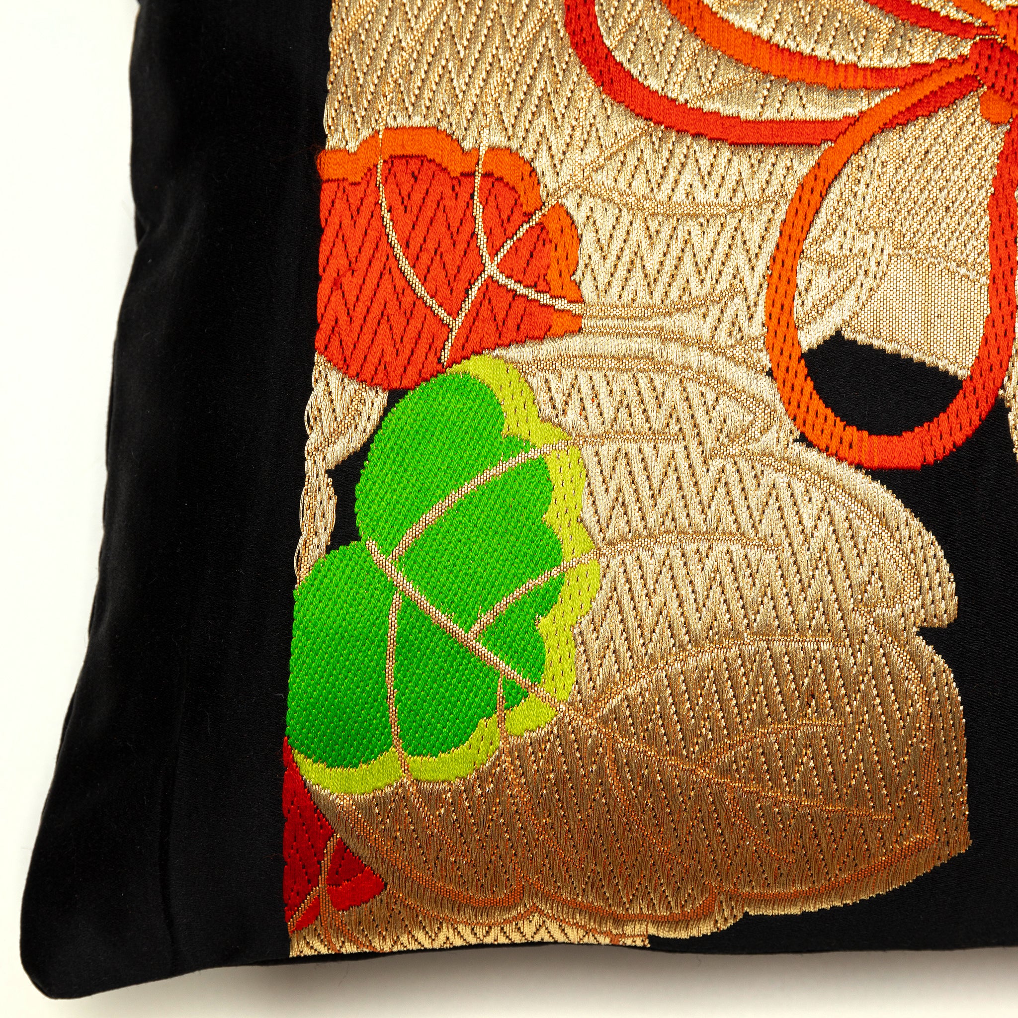 View of a corner of a vintage Japanes eobi pillow with black silk border and golden kiri leaf pattern.