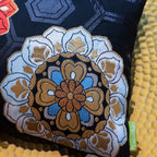 Detail of black silk pillow with hexagon pattern and a large blue and gold floral motif in the corner.