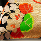 Close up detail of kiri paulownia motif in gold thread with red and green accents on a Japanese obi