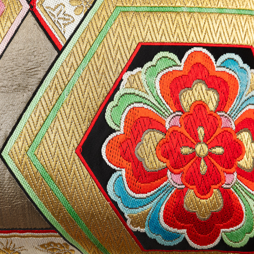 Close-up of woven vintage silk obi cushion with gilt thread zig-zags, hexagons and flowers.