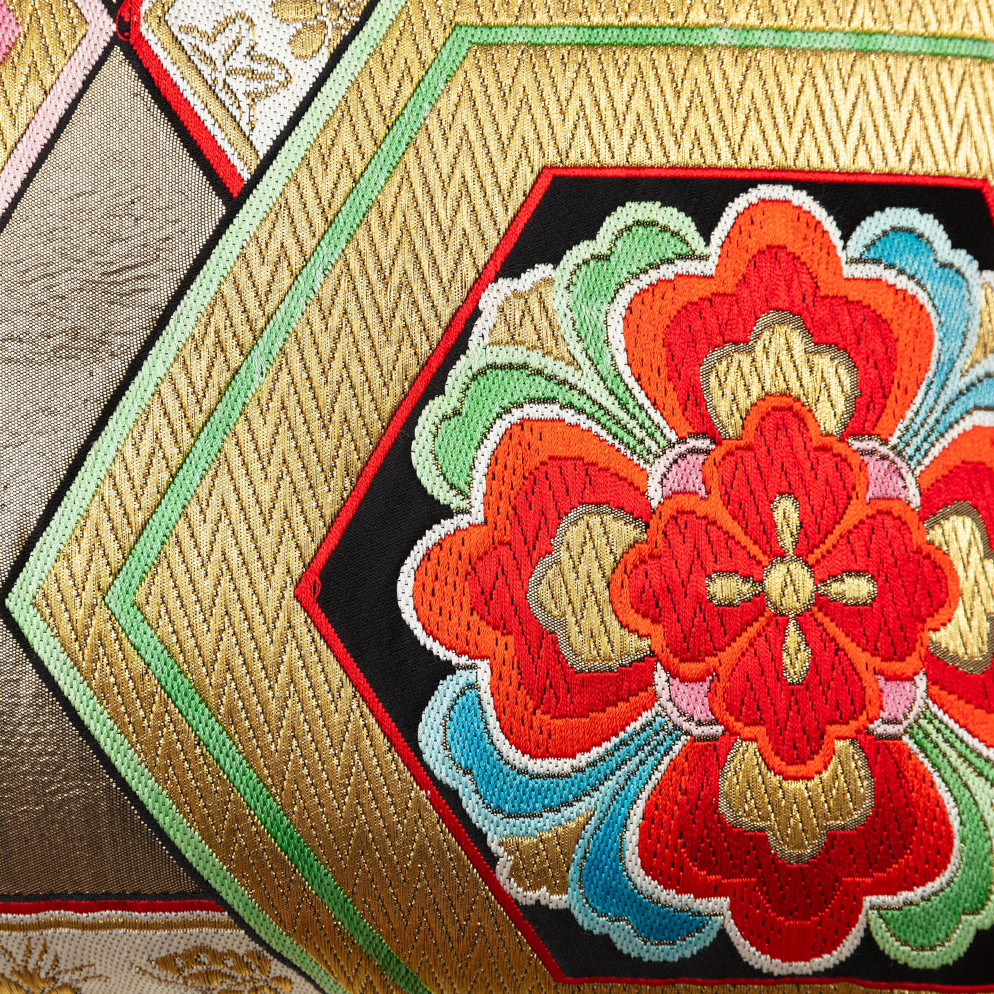 Close-up of woven vintage silk obi cushion with gilt thread zig-zags, hexagons and flowers.