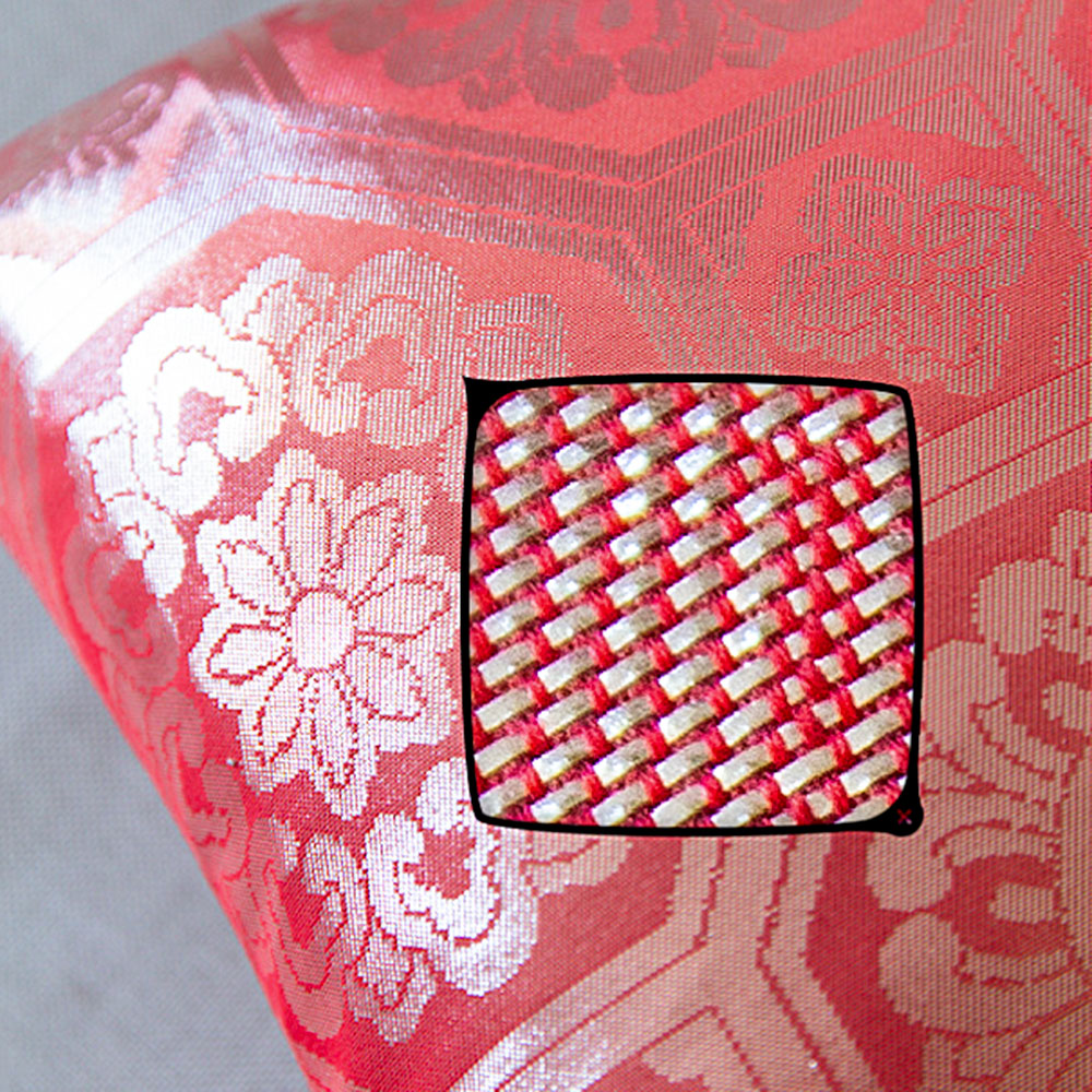 Close-up of the silver geometric obi pattern highlighting intricate embroidery on the pink silk surface of the 1930s throw