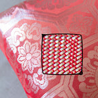 Close-up of the silver geometric obi pattern highlighting intricate embroidery on the pink silk surface of the 1930s throw