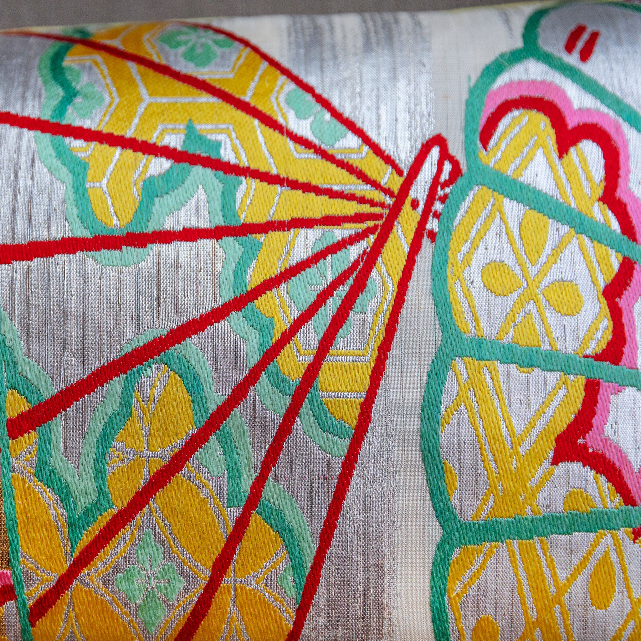 Close-up of silver Japanese obi bolster cushion with fan pattern embroidery made from vintage 1950s maru obi