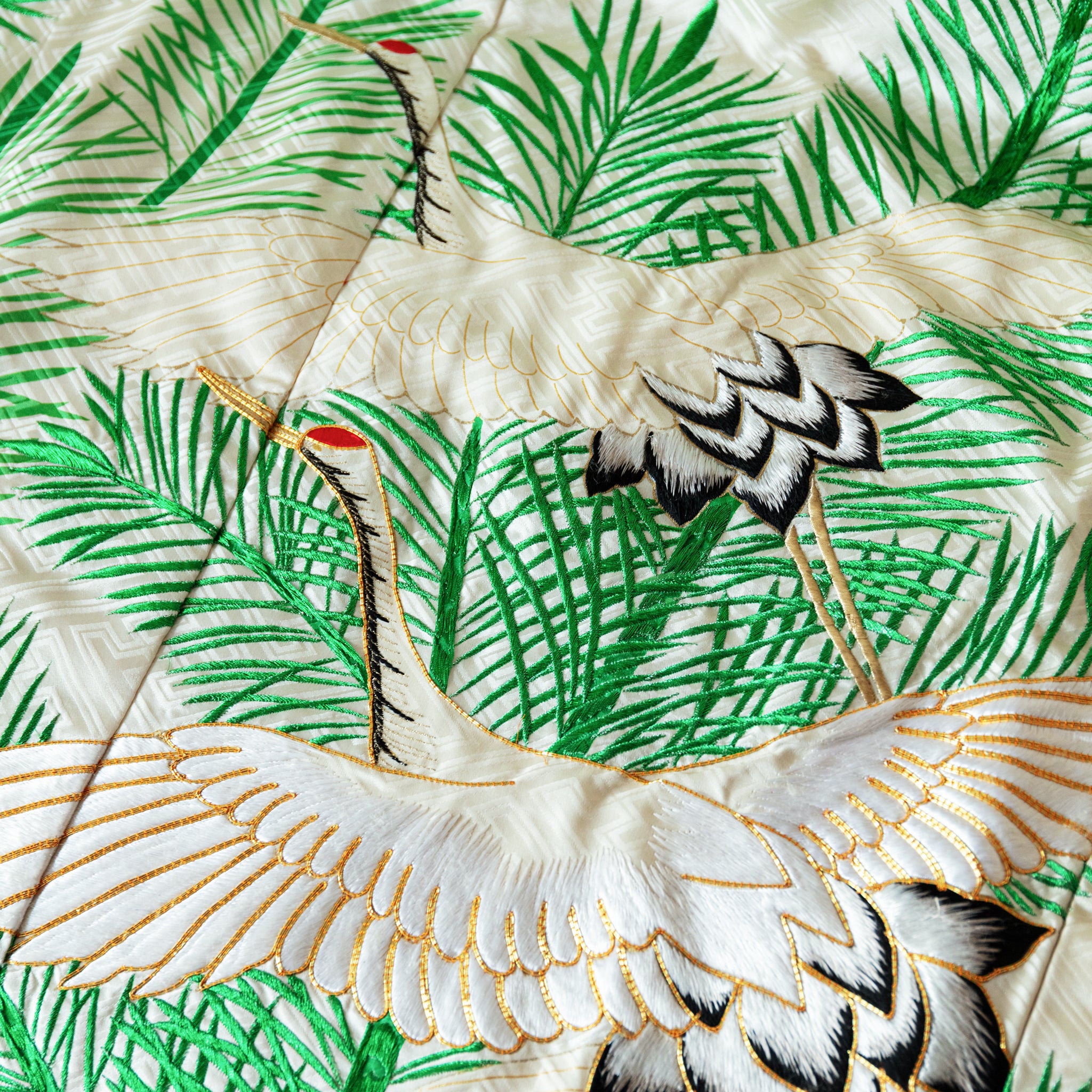 Cream silk throw made from vintage uchikake kimono silk, two flying cranes in white over green pine needles embroidery, close up