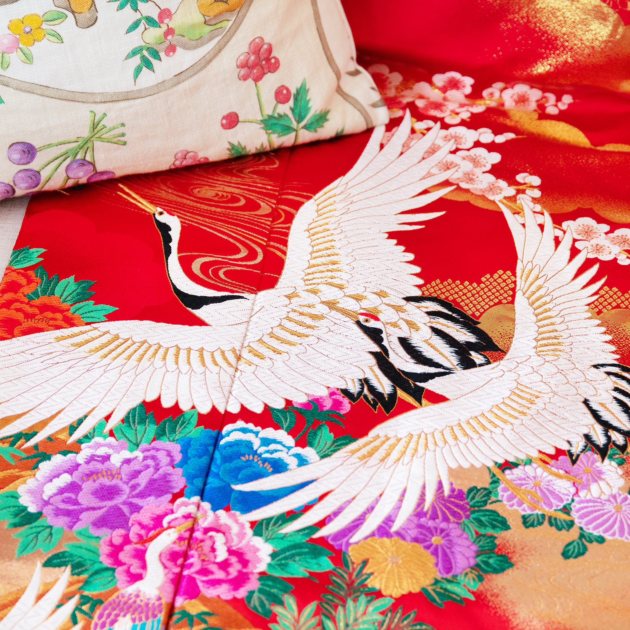 silk throw made from vintage kimono silk with white embroidered cranes over multicolour flowers on red, close up detail