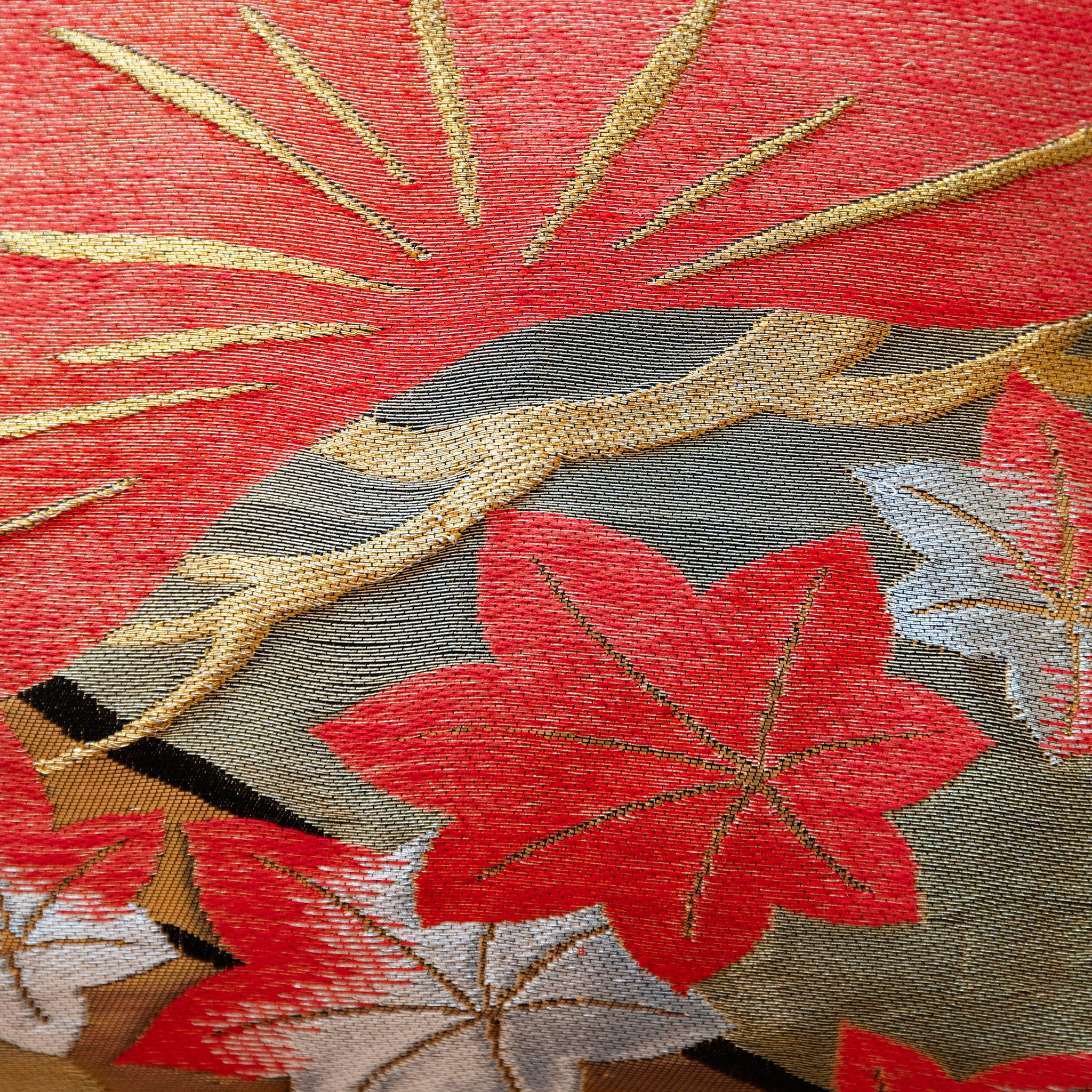 Close-up of peach velvet fabric with pines embroidery on the black obi pillow's corner, highlighting detailed stitching and