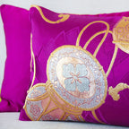 Detail of a woven silk gold Japanese drum on a purple silk cushion with the edge of a second purple silk cushion showing behind it.