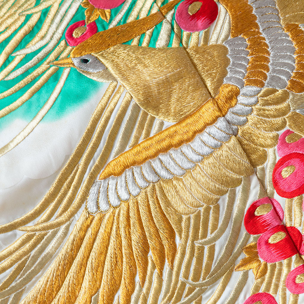 Close-up of intricate gold phoenix embroidery and vibrant silk textures on corner of vintage wedding kimono-inspired throw