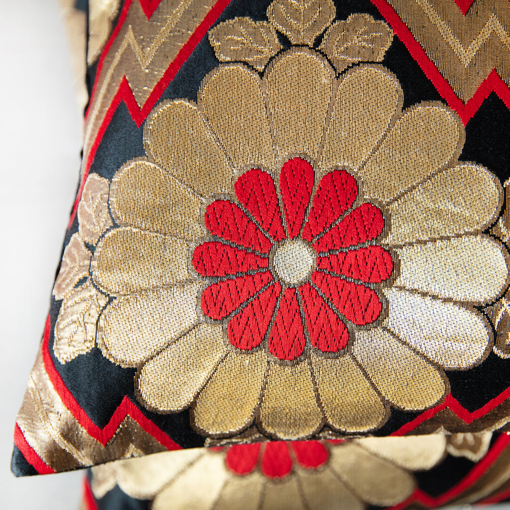 Detail of a gold and red chrysanthemum symbol on a black vintage silk obi cushion.