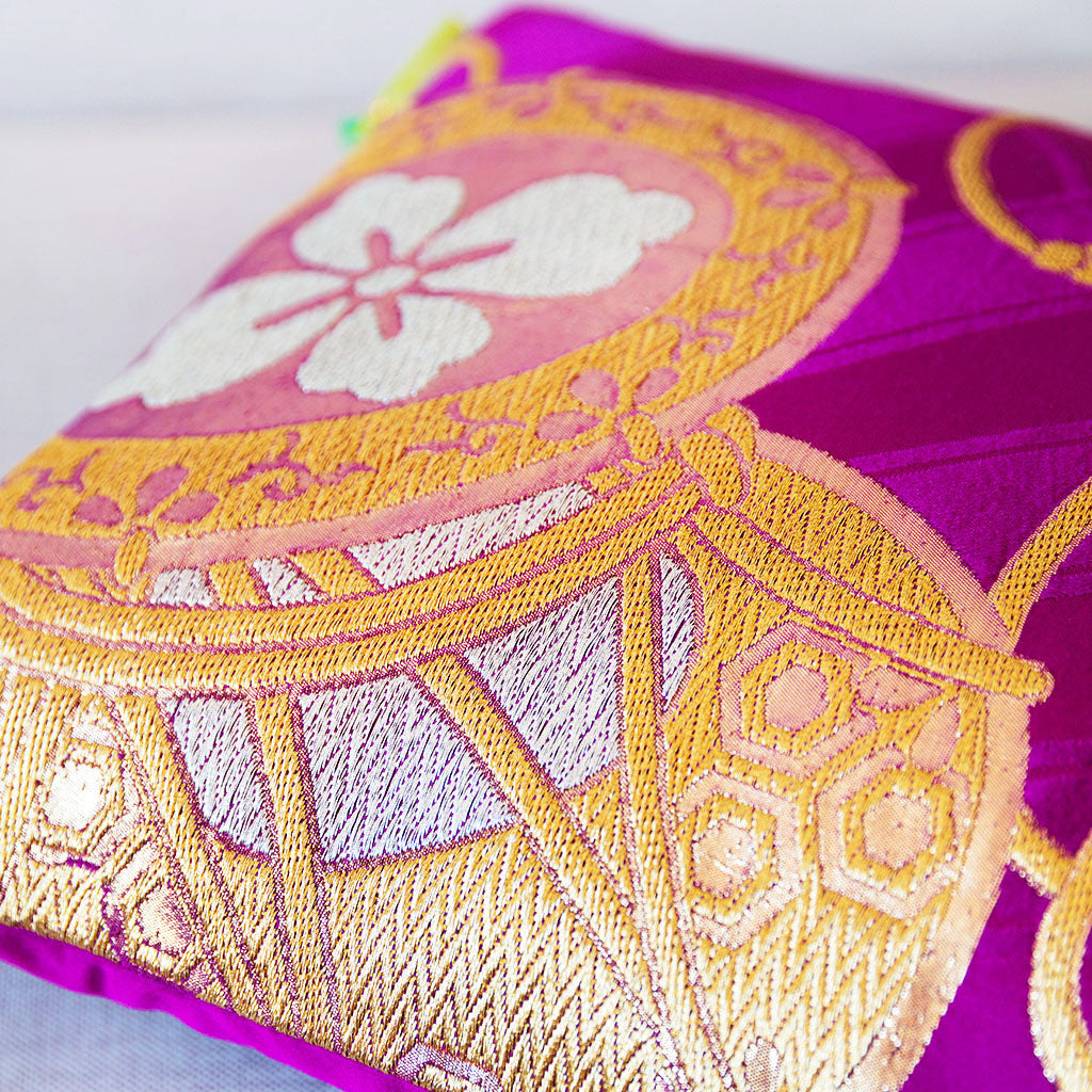 Close-up view of the woven gilt thread drum motif on a purple silk vintage Japanese cushion.