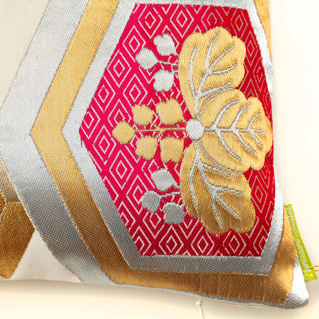 Close up detail of a red hexagon motif with a gold paulownia flower in the middle, from a vintage Japanese obi cushion in cream silk.