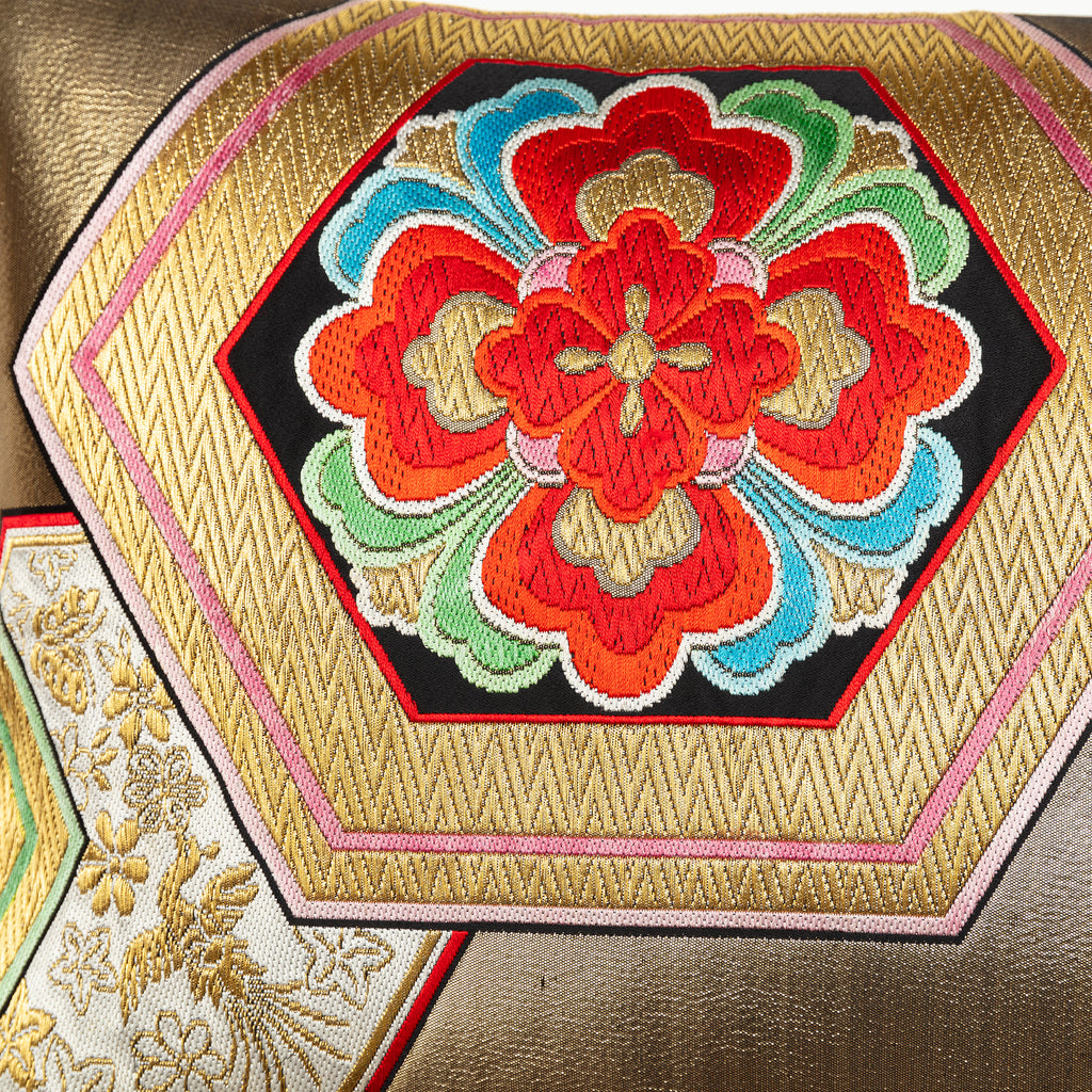 Detail of a red hanabishi floral motif on a vintage silk cushion in gold.