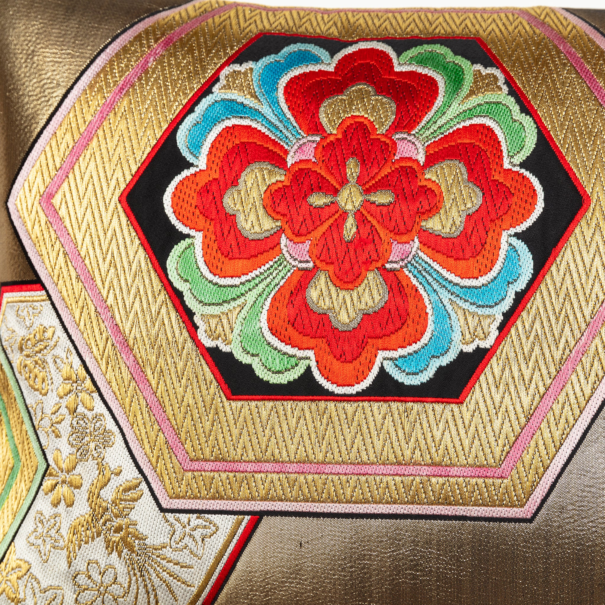 Detail of a red hanabishi floral motif on a vintage silk cushion in gold.