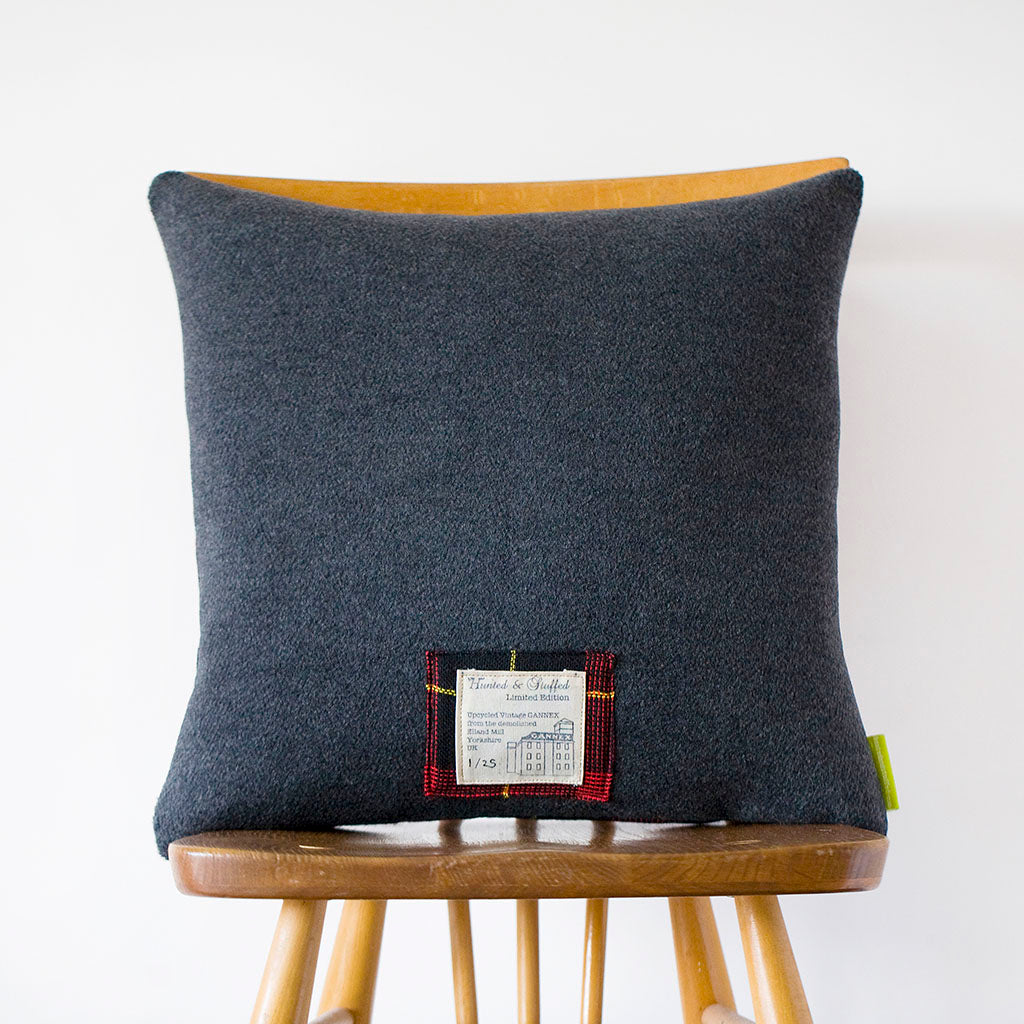 Close-up of grey tartan wool fabric showing intricate weave and soft texture detail from a slight diagonal angle.