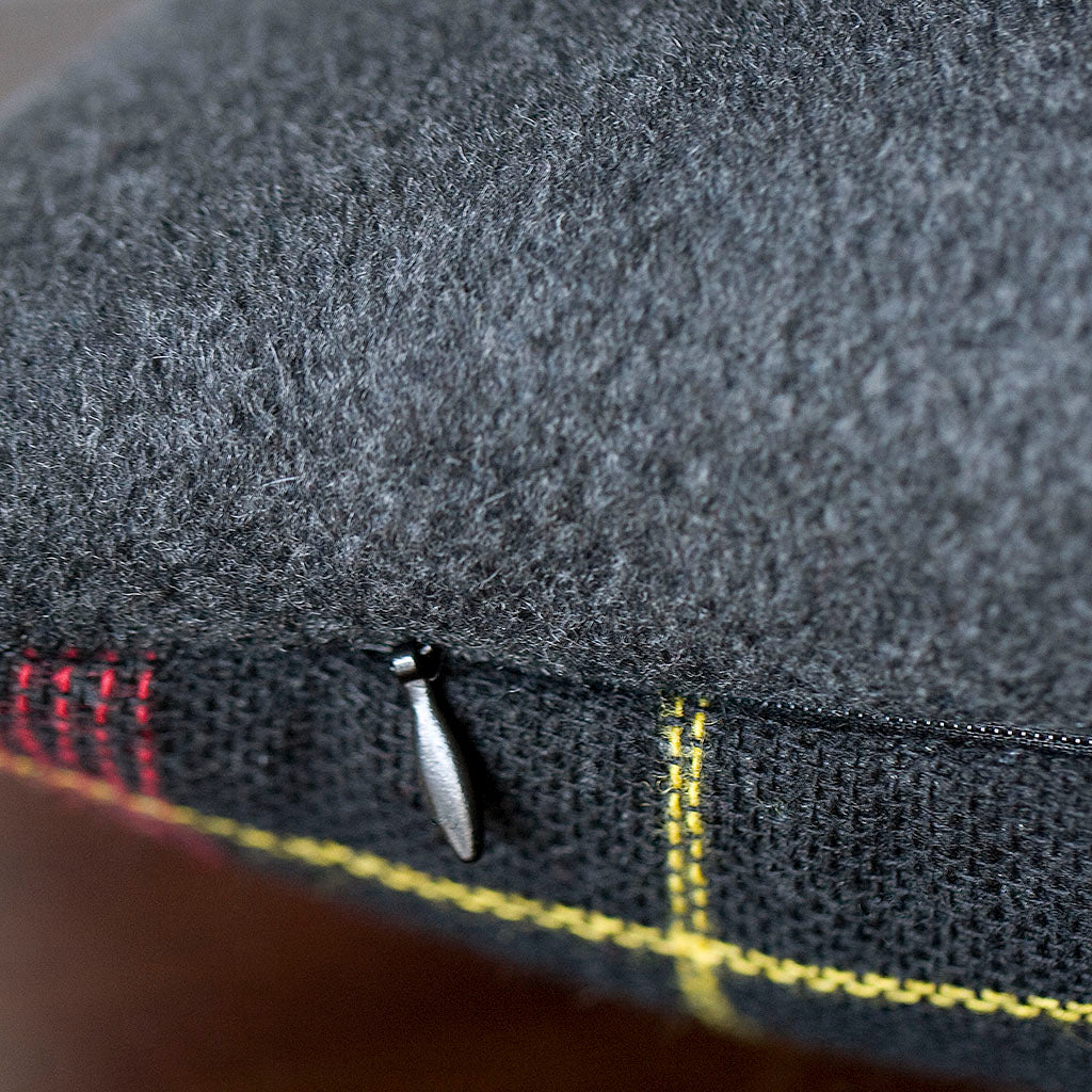 Close-up of grey tartan wool fabric highlighting textured weave and subtle color variations in the cushion cover.