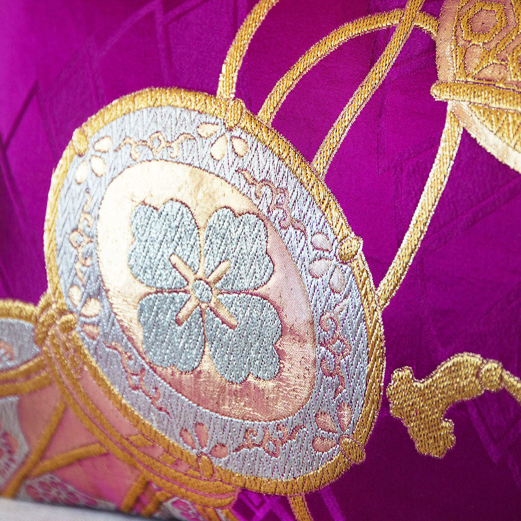 Silver and gold drum design on a purple silk obi cushion, close up detail.
