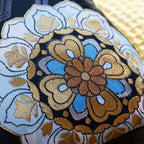 Detail of blue and gold floral symbol on black silk vintage Japanese obi cushion
