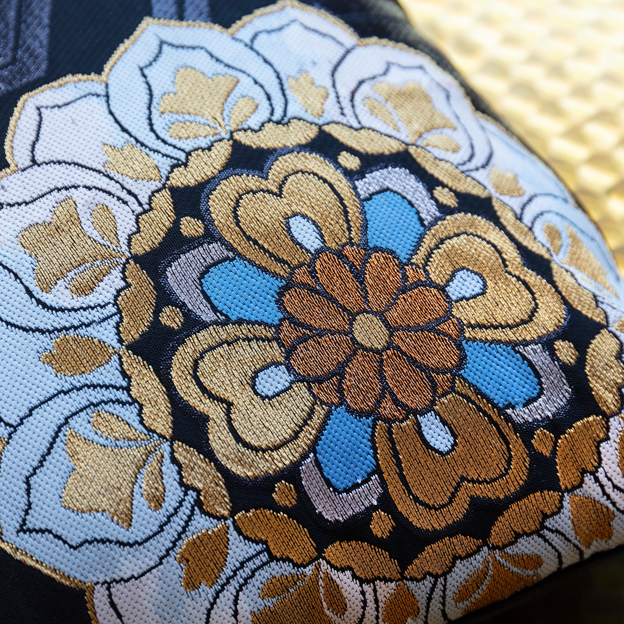 Detail of blue and gold floral symbol on black silk vintage Japanese obi cushion