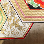 Detail of a gold phoenix motif on a pale background and golden hexagons on a vintage Japanese obi cushion