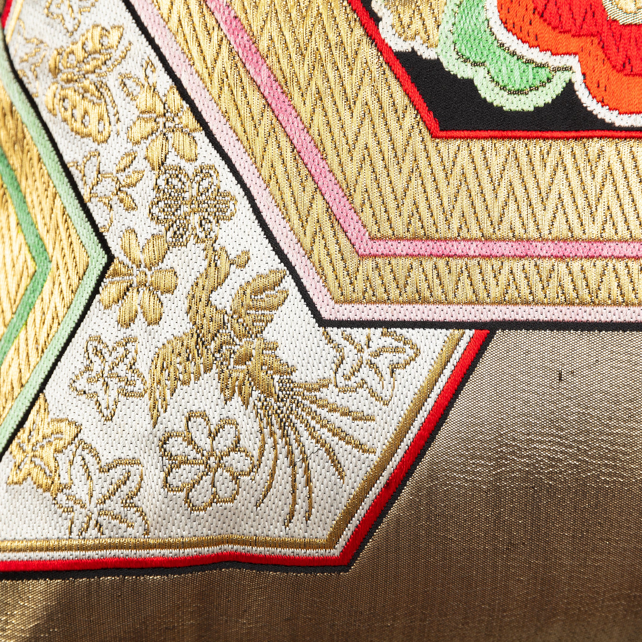 Detail of a gold phoenix motif on a pale background and golden hexagons on a vintage Japanese obi cushion