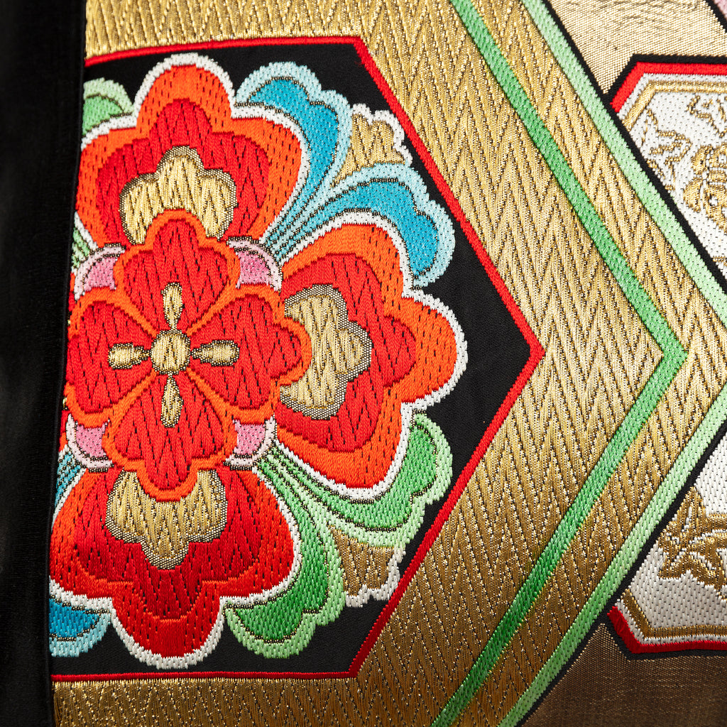 Detail of a woven gold obi with hexagon pattern and red flower motif.