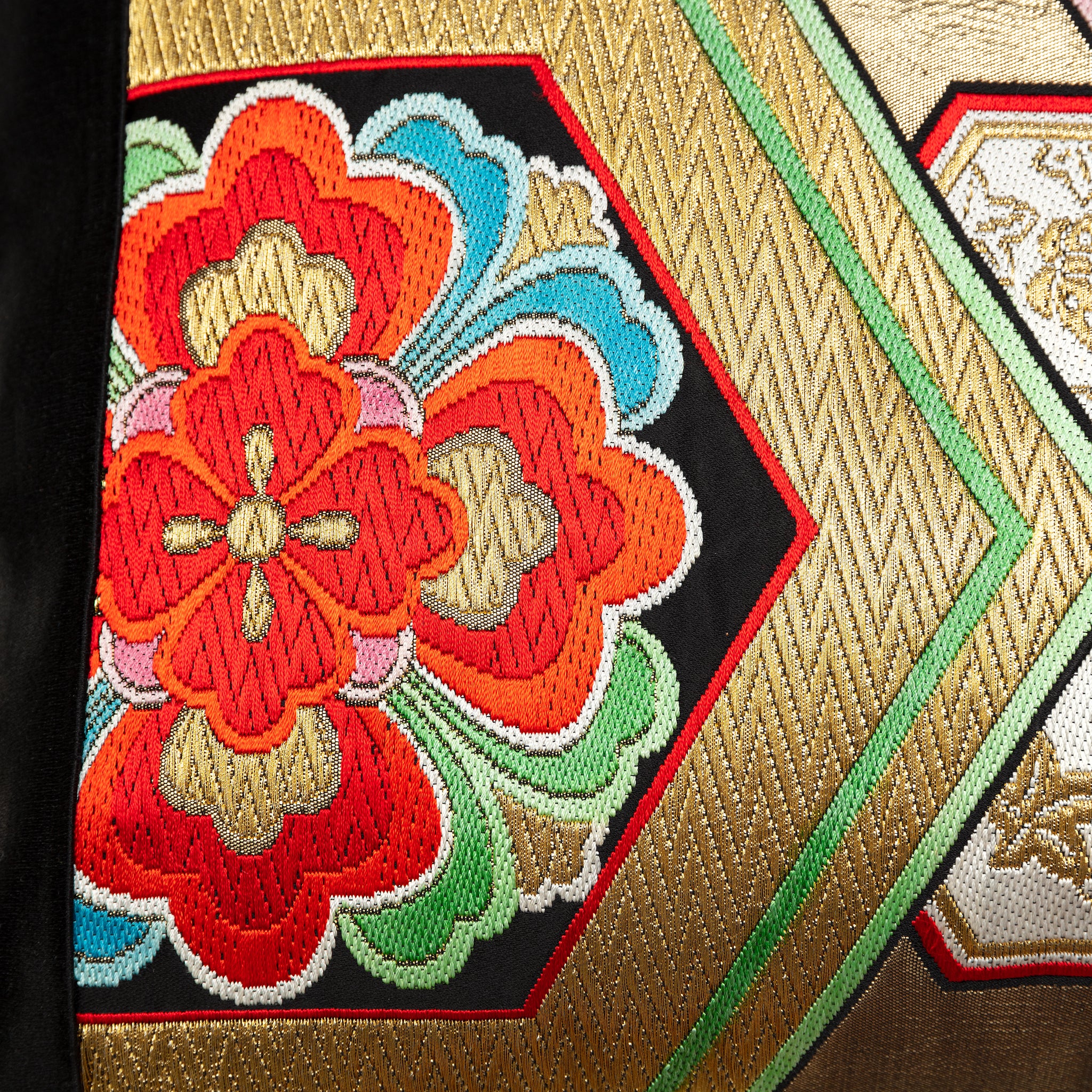 Detail of a woven gold obi with hexagon pattern and red flower motif.